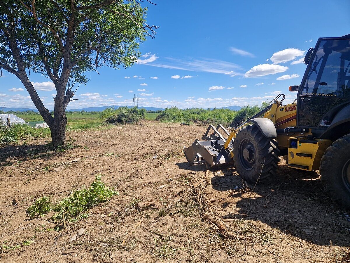 Traktorbáger New Holland pri čistení a úprave pozemku pri Michalovciach